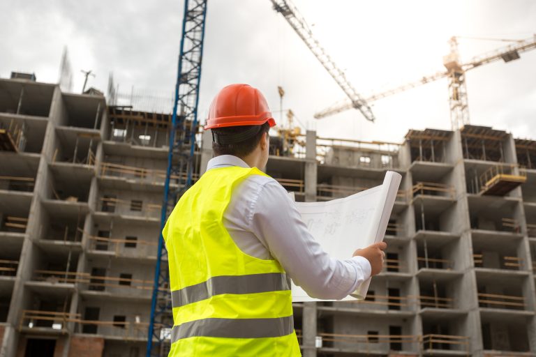 Engineer on building site examines blueprints
