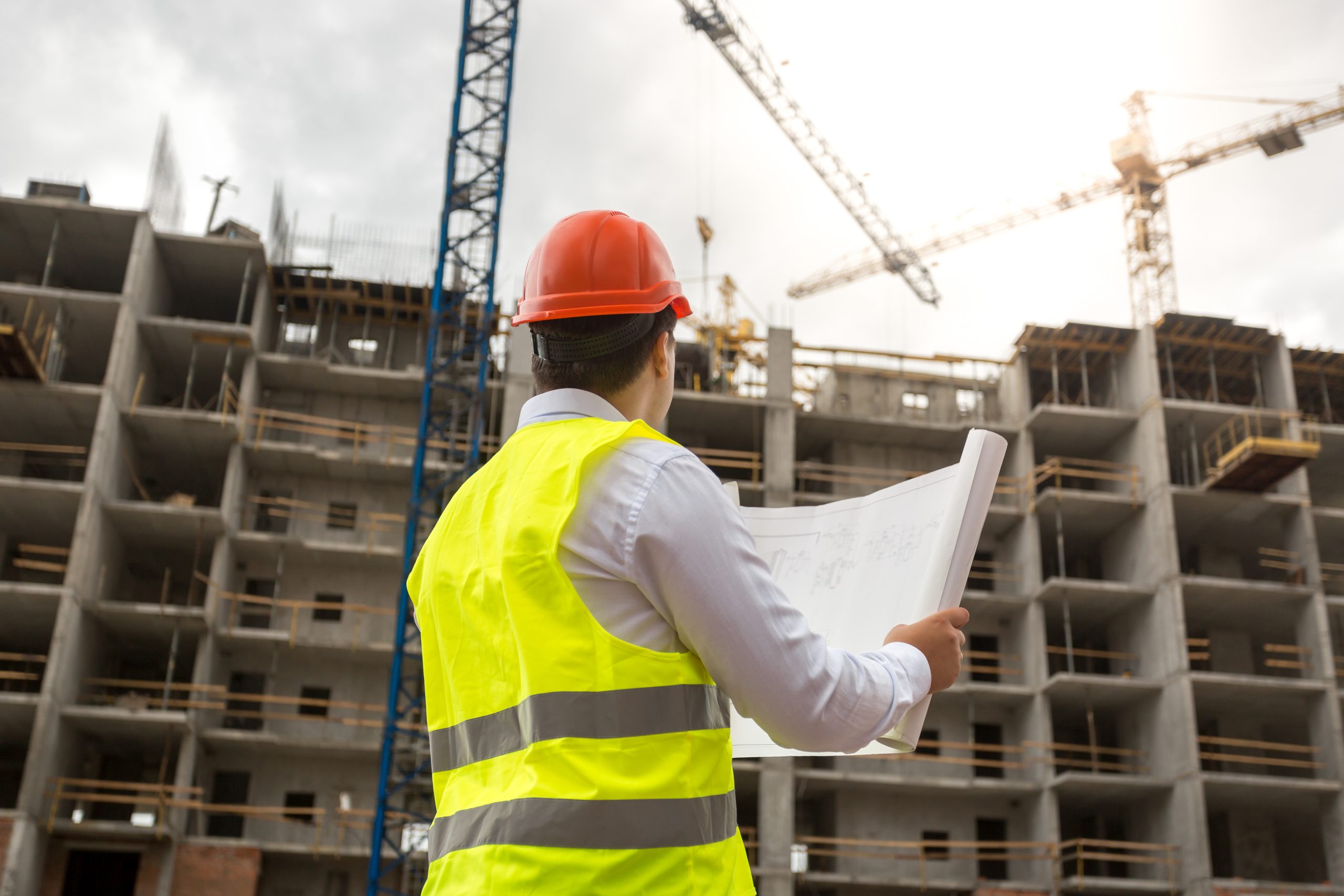 Engineer on building site examines blueprints